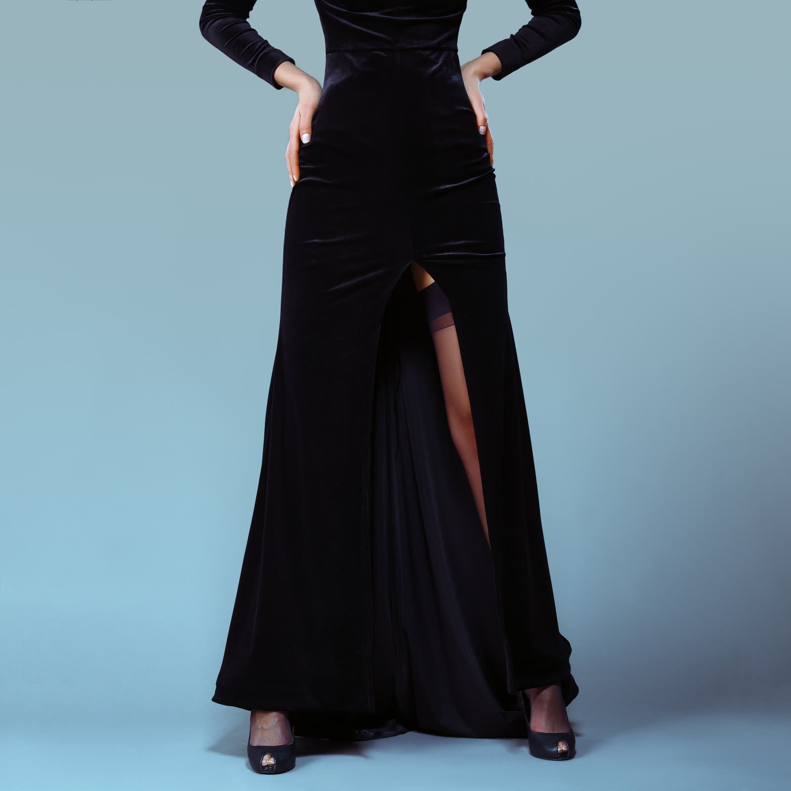 Floor-length black velvet gown with a front slit and long sleeves