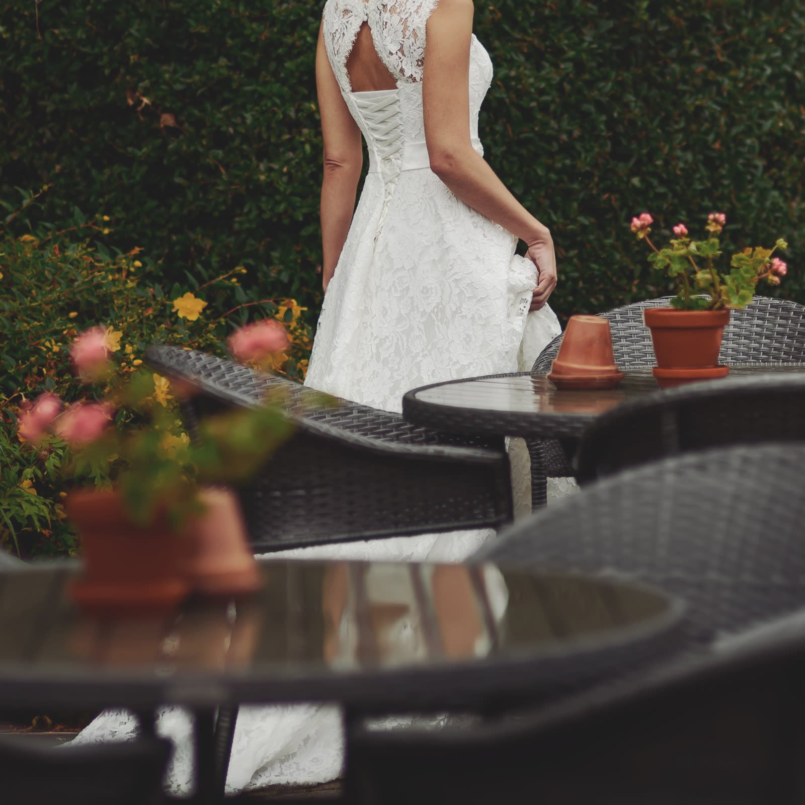 Back of a white lace dress with a lace-up bodice, seen in a garden