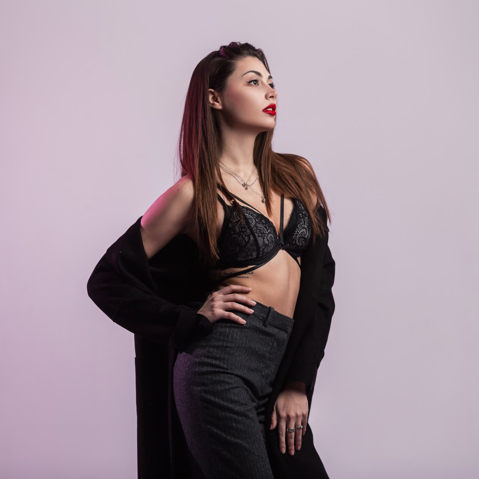Black lace bralette top styled with high-waisted trousers and a long black coat