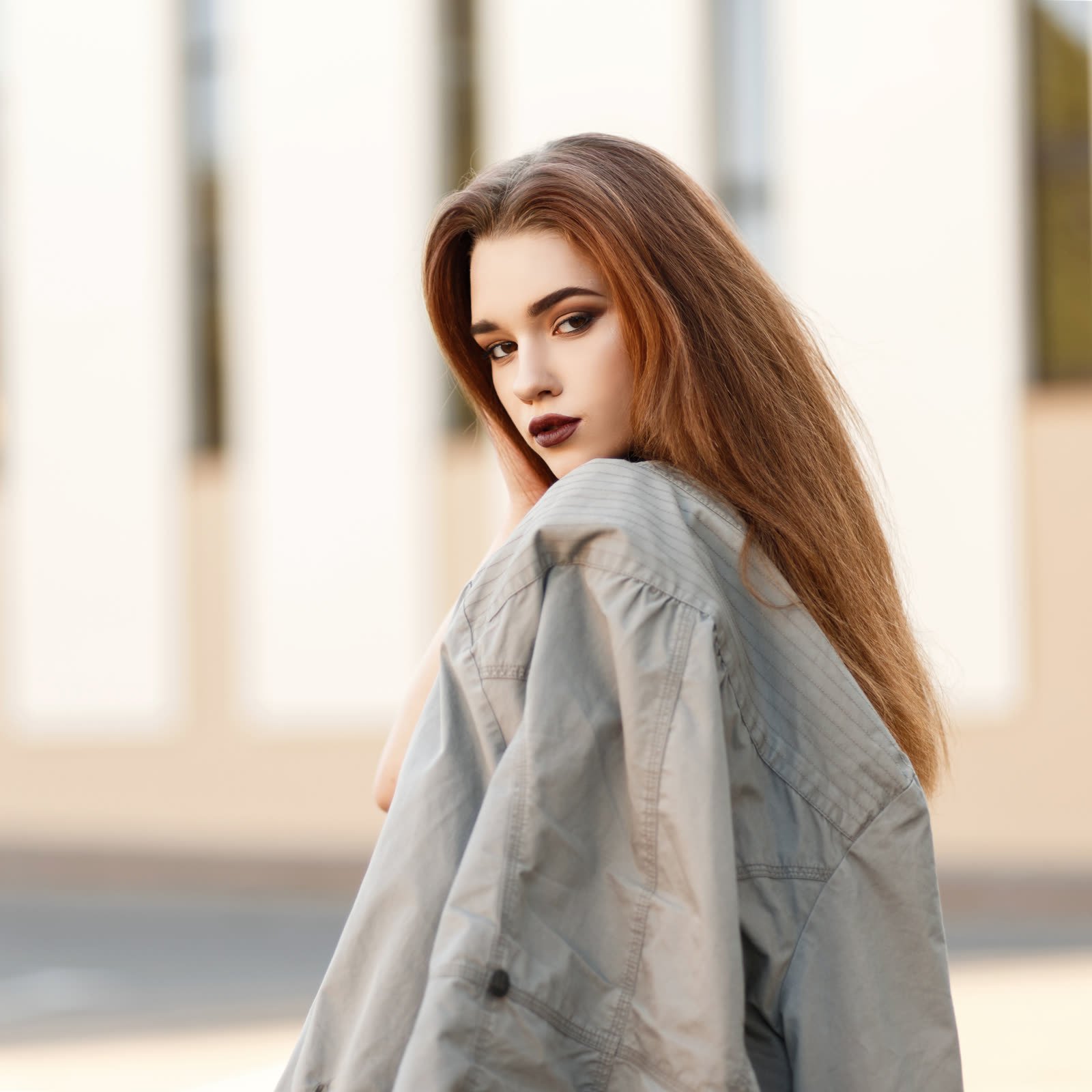 Woman with long hair in an oversized jacket slipping off one shoulder