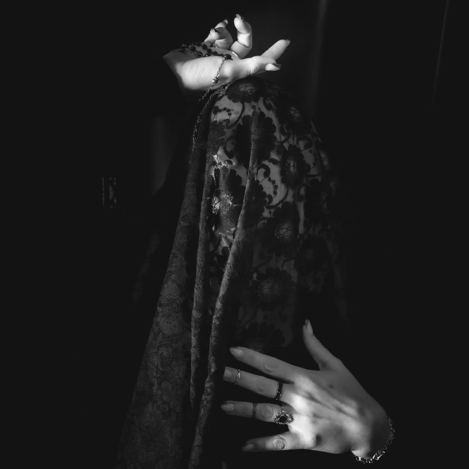 Black floral lace draped over a woman in deep shadow