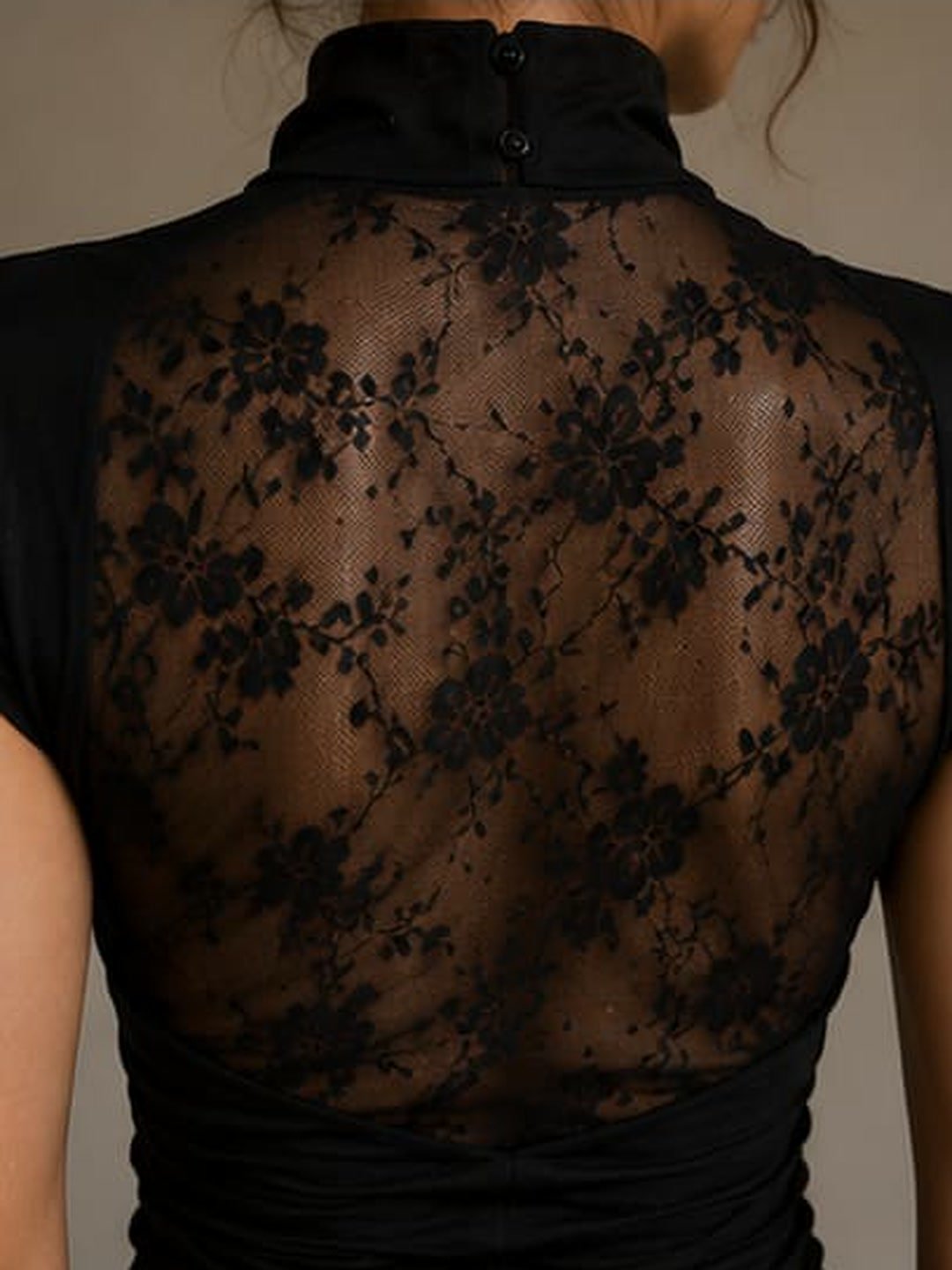 Close-up of a black high-neck top with a sheer floral lace back panel