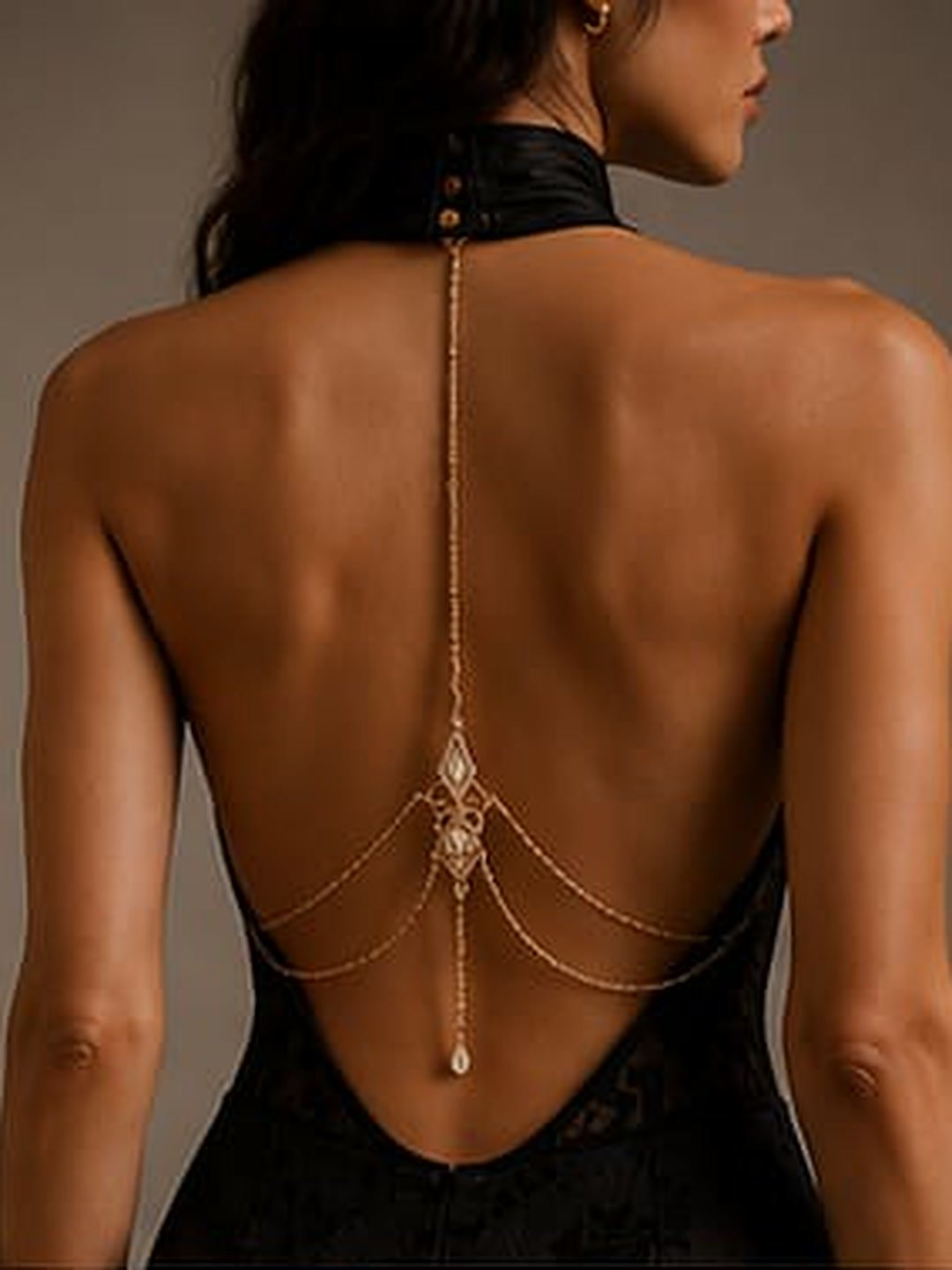 Open back of a black halter gown with a fine gold back chain